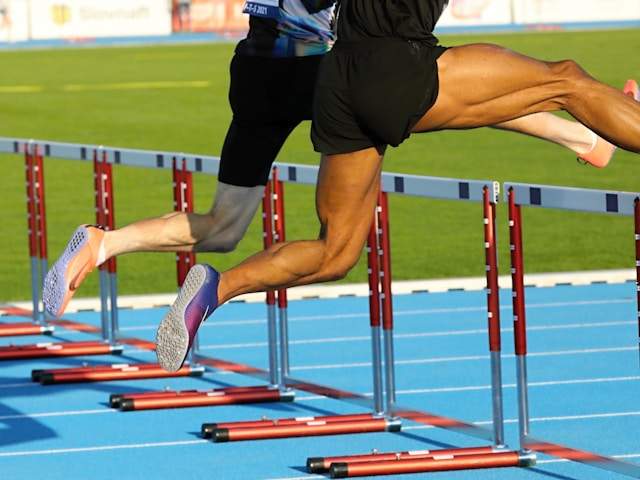 men jumping over hurdles